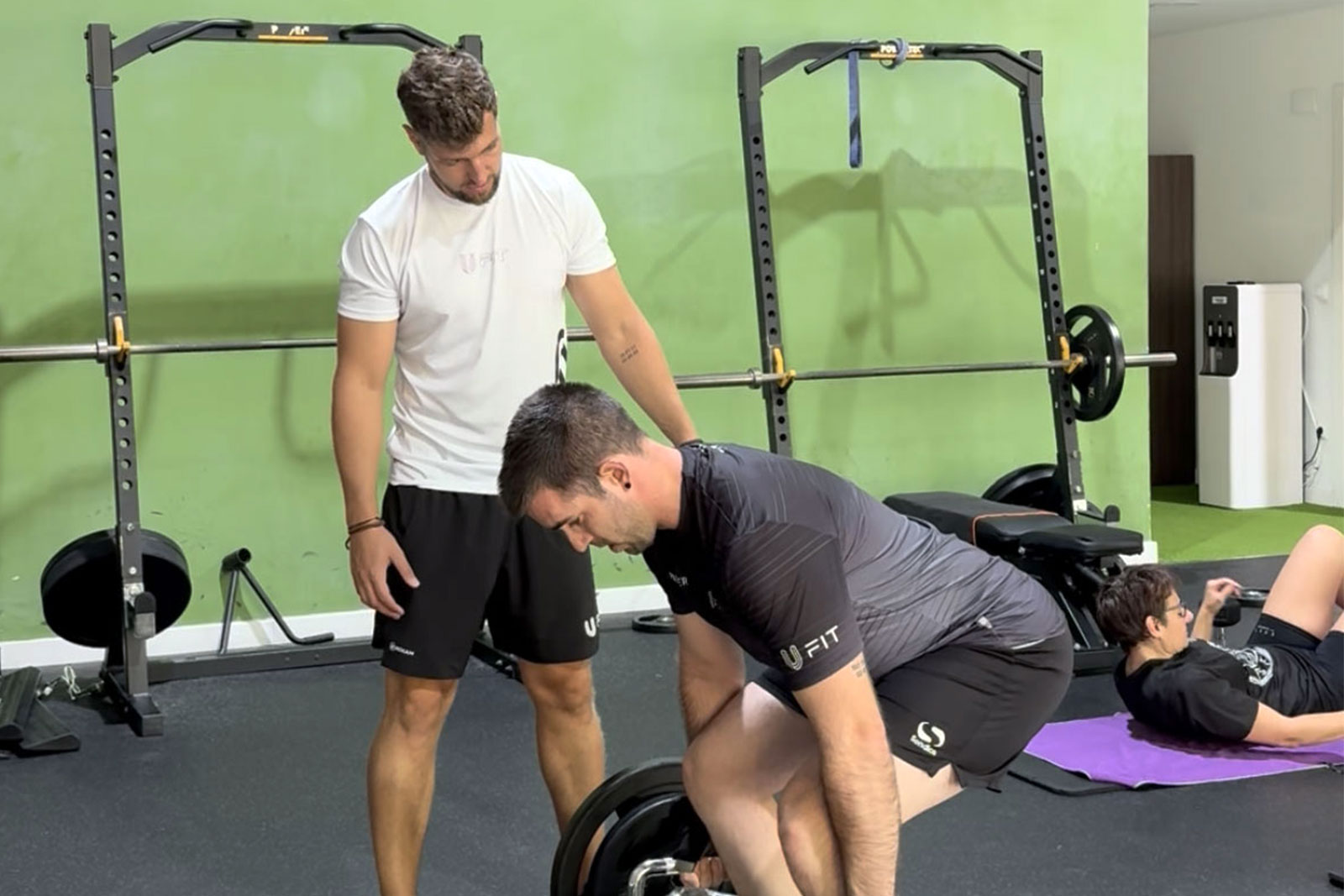 Entrenador de UFIT corrigiendo la técnica de un peso muerto